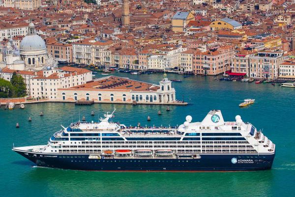 Drone shot of cruise ship with houses with orange roofs in the background