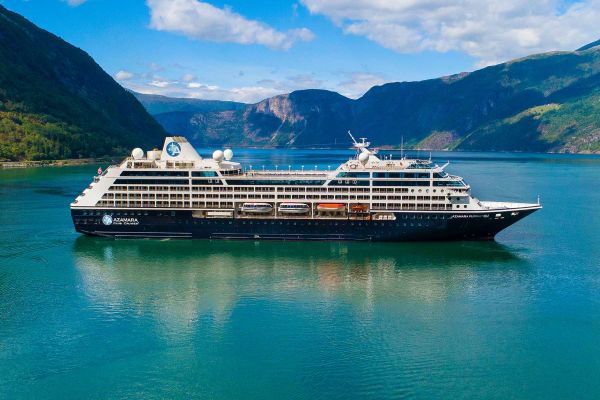 Cruise ship in the turquoise ocean with green hills in the distance