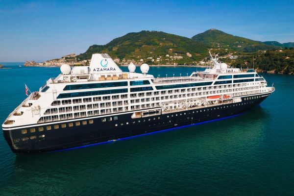 Cruise ship in the turquoise ocean with a green hill in the distance