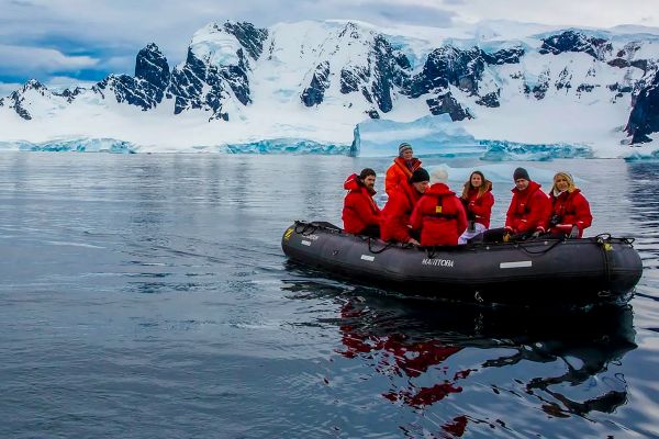 Group of people in a little expedition boat looking at glaciers