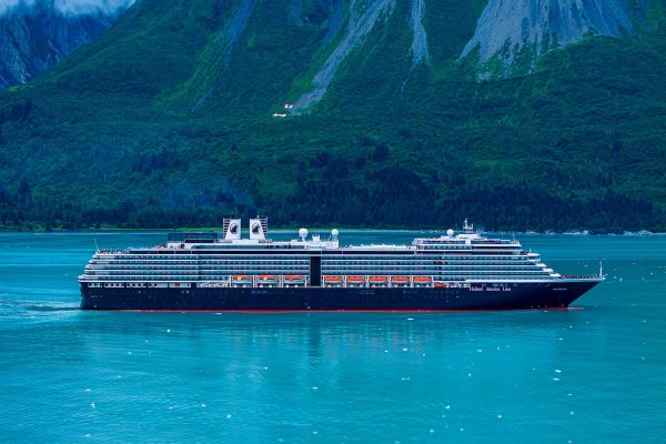 Cruise ship in the turquoise ocean with a green hill in the distance