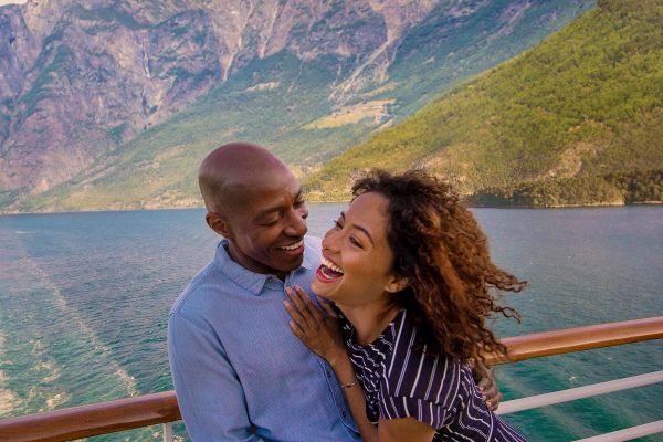 Couple laughing on ship with green hills in distance