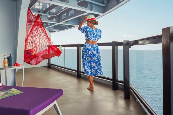 Woman in blue & white beach outfit walking towards a red hammock on a cruise ship