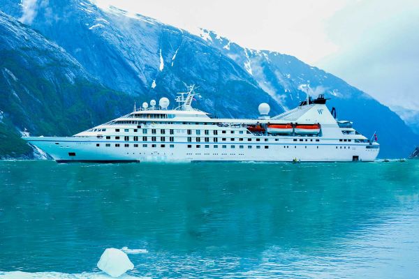 Windstar cruise ship next to a snow tipped mountain