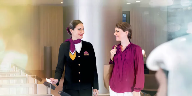 Qatar Airways escort assisting passenger with directions in Al Maha Airport.