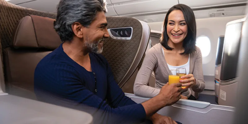 Singapore Airlines business class seats with couple enjoying a beverage over the divider.