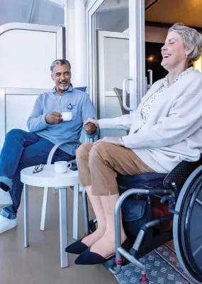 A woman using a wheel chair enjoy time on a ship's balcony with her partner.