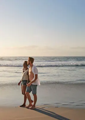 A loving couple walking on the beach as the sun rises