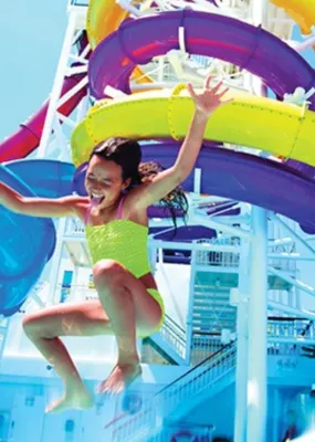 A girl jumps into a pool in a waterpark on board a cruise ship