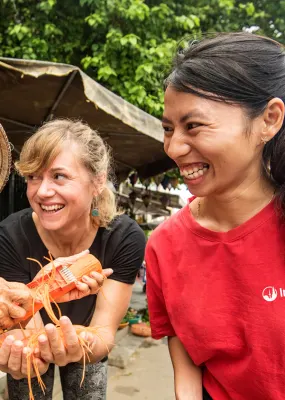 An Intrepid tour guide with a traveller and a food market vendor in Vietnam
