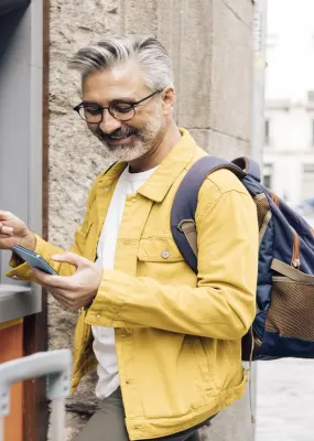 Man looking at phone and taking money out of an ATM