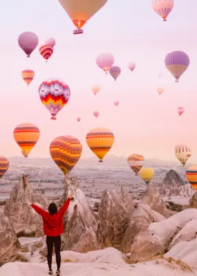 A woman watches a sky full of hot air balloons in Cappadocia, Turkiye