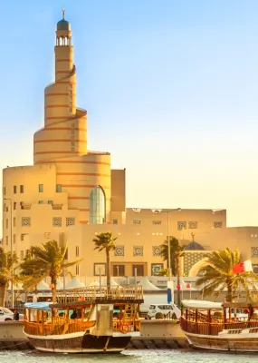 Unique spiral architecture on the waterfront in Qatar lined by palm trees and boats