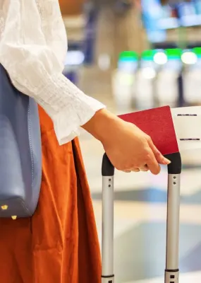 lady at airport holding ticket and passport