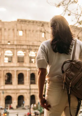 Lady with backpack facing the Colosseum in Italy