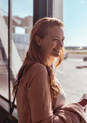 female traveller standing at window in airport smiling