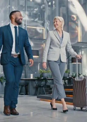 Man and lady pulling suitcases through building