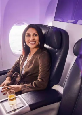 Lady sitting on airplane seat smiling at flight attendant