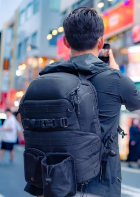 man wearing large backpack taking photo on street in japan