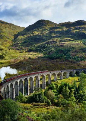 train running over bridge in mountains of scotland