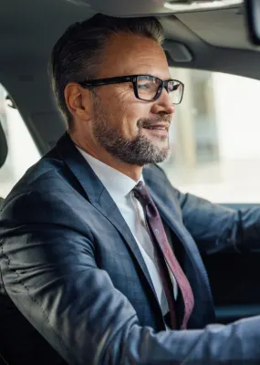 A man in a business suit driving a car