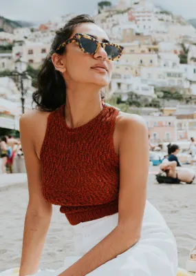 Lady sitting on beach in italy with cliff full of buildings in background