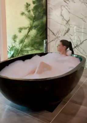 Lady enjoying a bubble bath while a bear approaches