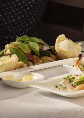 a person enjoying a fancy chicken salad meal and a glass of red wine while on his flight
