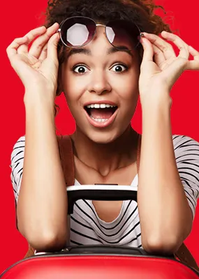 a surprised looking curly woman with a red luggage