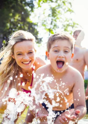 Family of three enjoying the water in their garden