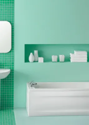 a restroom with white furniture and accessories and green tiles