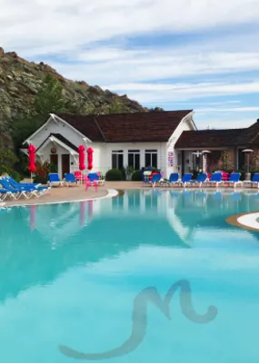 a big pool with blue lounge reclining pool chairs and red umbrellas