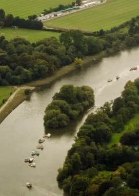Settlement by a river surrounded by acres of green land and trees