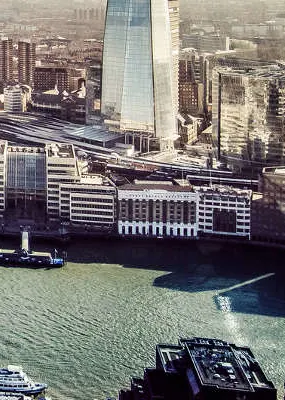 City buildings near the lake with a ship crossing and boats parking on the side