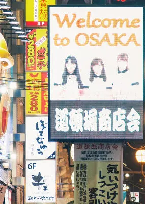 view of street in Osaka Japan with a welcome to Osaka illuminated lightbox signage