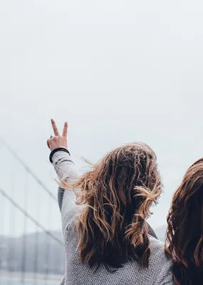 two female friend holding up a peace sign while looking at the bridge