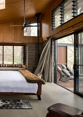 a wooden themed room with a white king sized bed and white cocoon-like hanging lamps