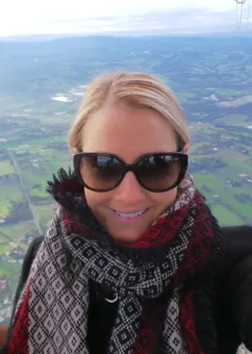 Woman in an air balloon wearing sunglasses and a red and black scarf 
