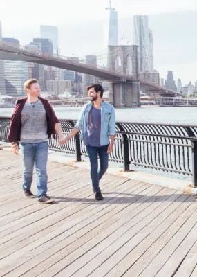 couple walking holding hands with Brooklyn Bridge in background