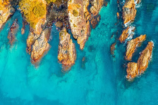Aerial shot of clear water up against rock face