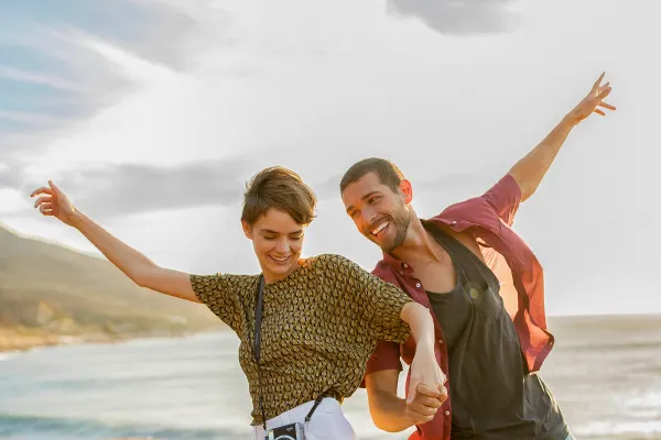 Two people holding hands and smiling near ocean