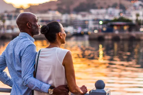 A couple standing on a verendah overlooking the water