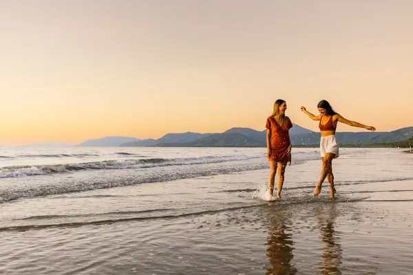 Two women happily walking and splashing through the surf in the early afternoon