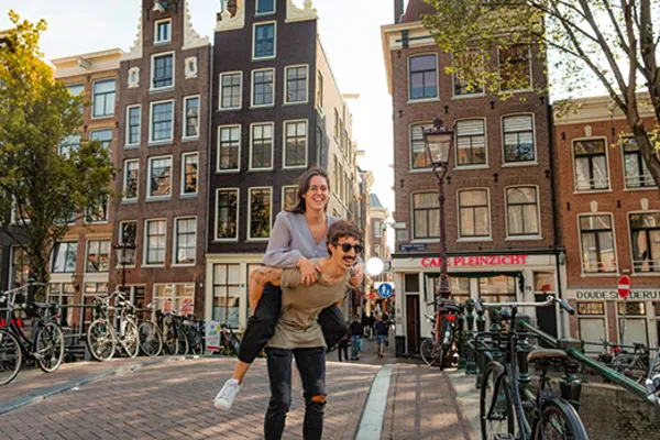 man giving woman piggyback on the streets of amsterdam