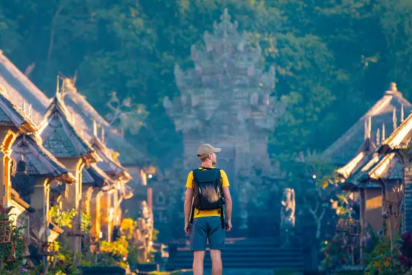 Tourist with backpack exploring Penglipuran historical village on Bali island 
