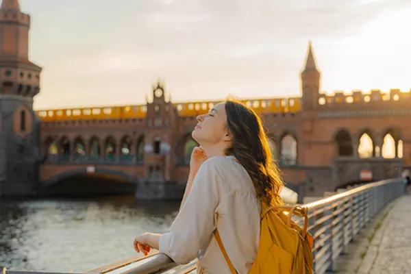 girl leaning over railing of bridge over river in berlin