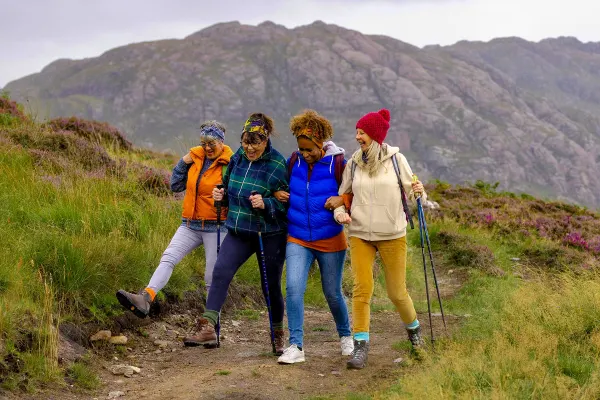 Four woman laughing and hiking along a dirt path