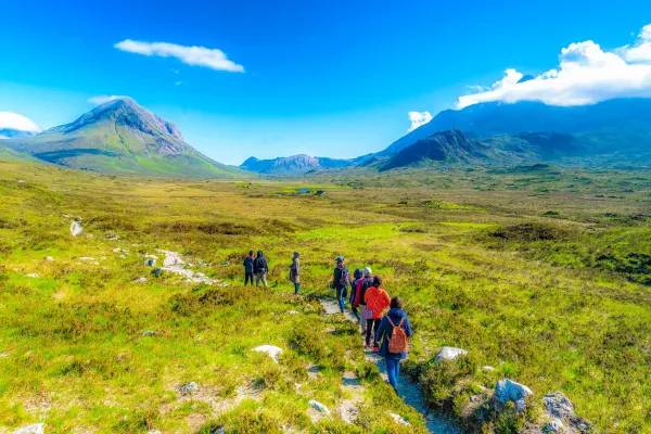 Tourists walking through a grassy plain towards mountains