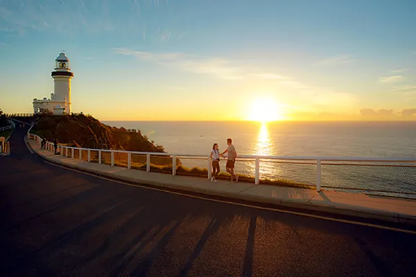 Couple on a walkway leading to a lighthouse at sunset