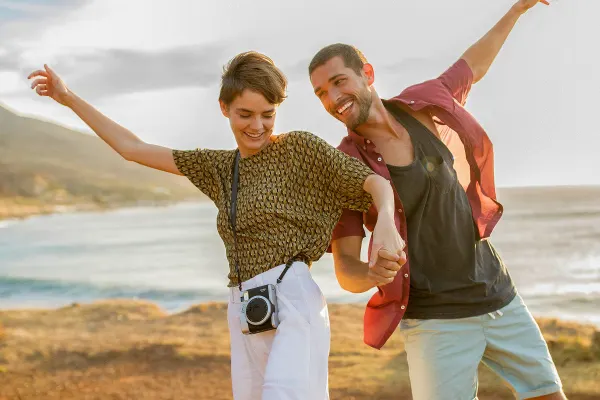 Two people holding hands and smiling near ocean
